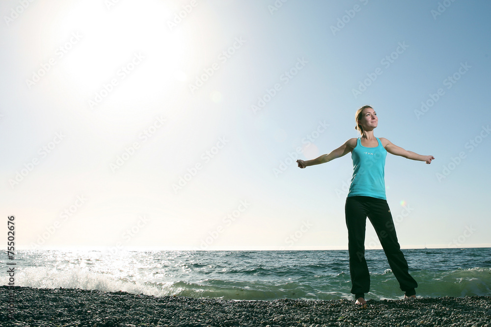 Ordinary woman stretching hands on beach. Training on beach.