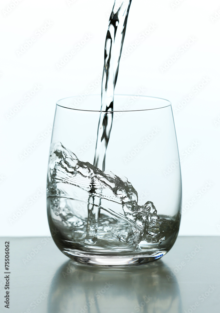 Pouring water from bottle on glass isolated on white Pouring water from bottle on glass isolated on white