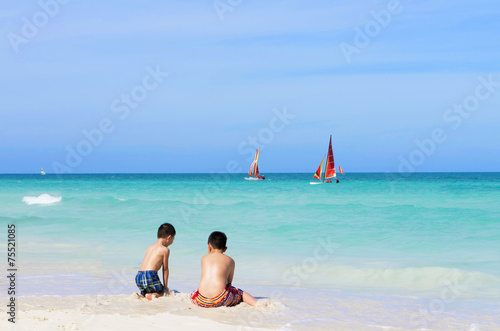 Two Asian boys playing on the white sandy beach in Cayo Santa Ma photo