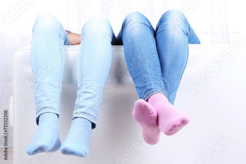 Male and female legs on sofa close-up