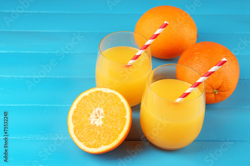 Glass of orange juice with straws and slices