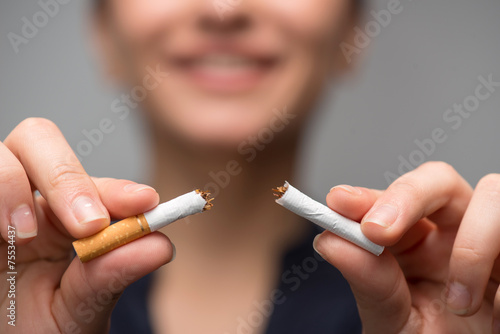 Addiction. Closeup of young attractive woman breaking cigarettes photo