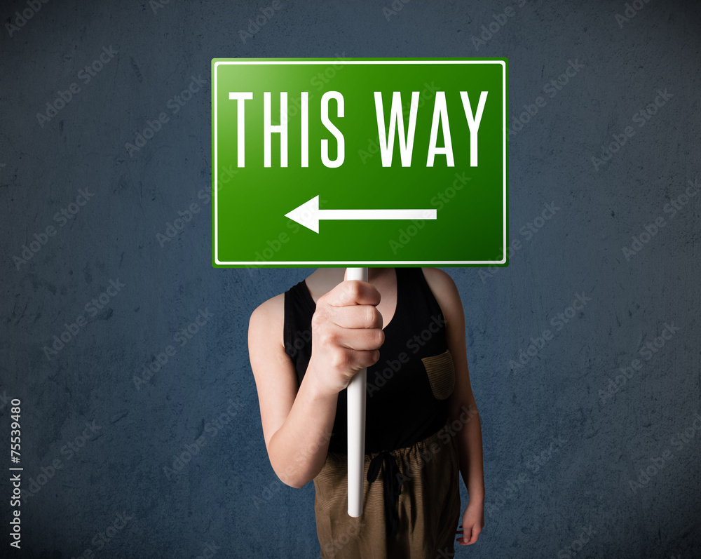 Young woman holding a direction sign Young woman holding a direction sign