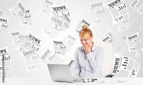 Business woman at desk with stock market newspapers