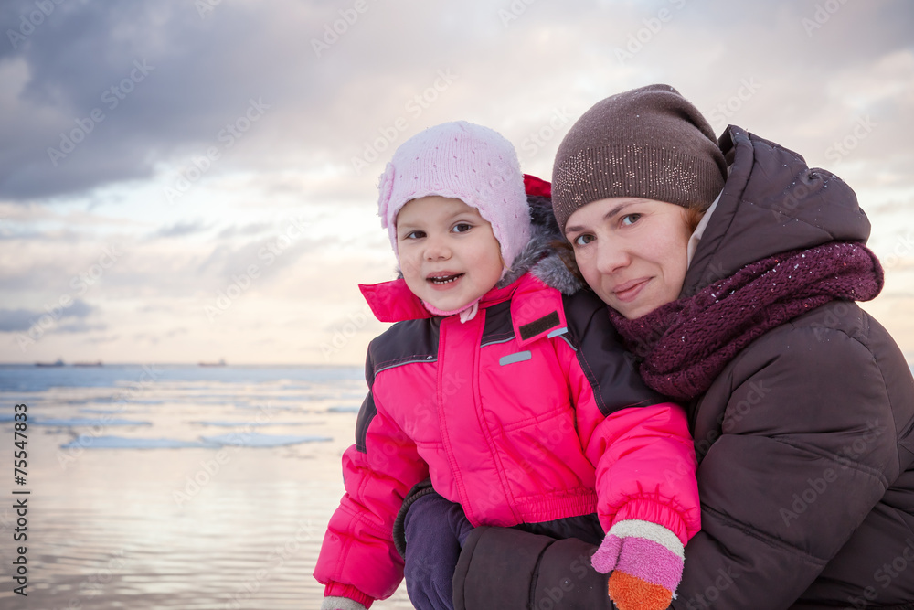 Caucasian family portrait on winter coast, mother hugs her girl Caucasian family portrait on winter coast, mother hugs her girl