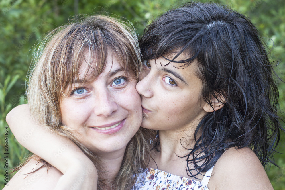 Daughter teenager kissing his young mother outdoors. Daughter teenager kissing his young mother outdoors.
