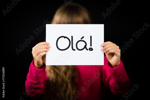 Child holding sign with Portuguese word Ola - Hello