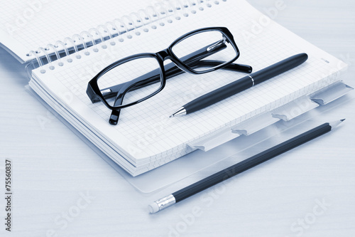 Office table with glasses, blank notepad and pencil
