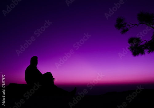 silhouette of man sitting on rock