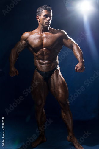 Strong muscular man bodybuilder in full growth. © kanzefar