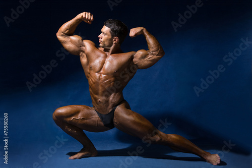 Strong muscular man bodybuilder shows his muscles.