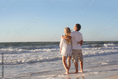 Happy Couple Looking out Over Ocean While Walking on Beach