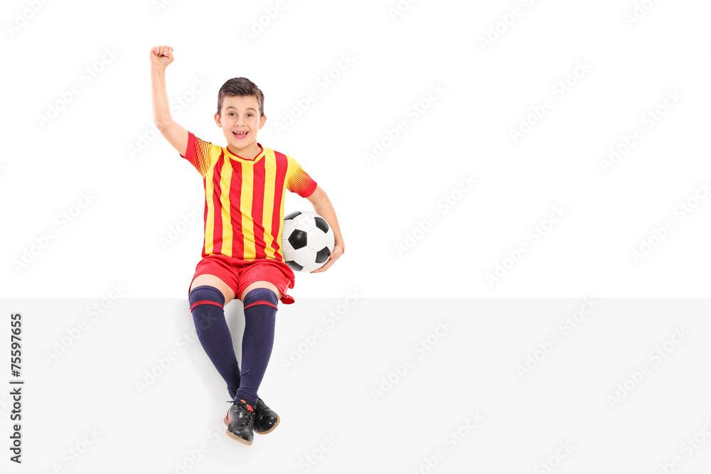 Junior soccer player gesturing joy seated on panel