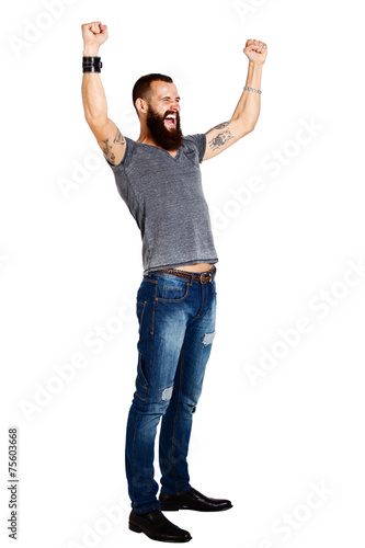 Excited handsome Tattooed bearded man with arms raised in succes