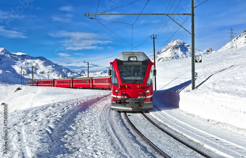 A red swiss train running through the snow