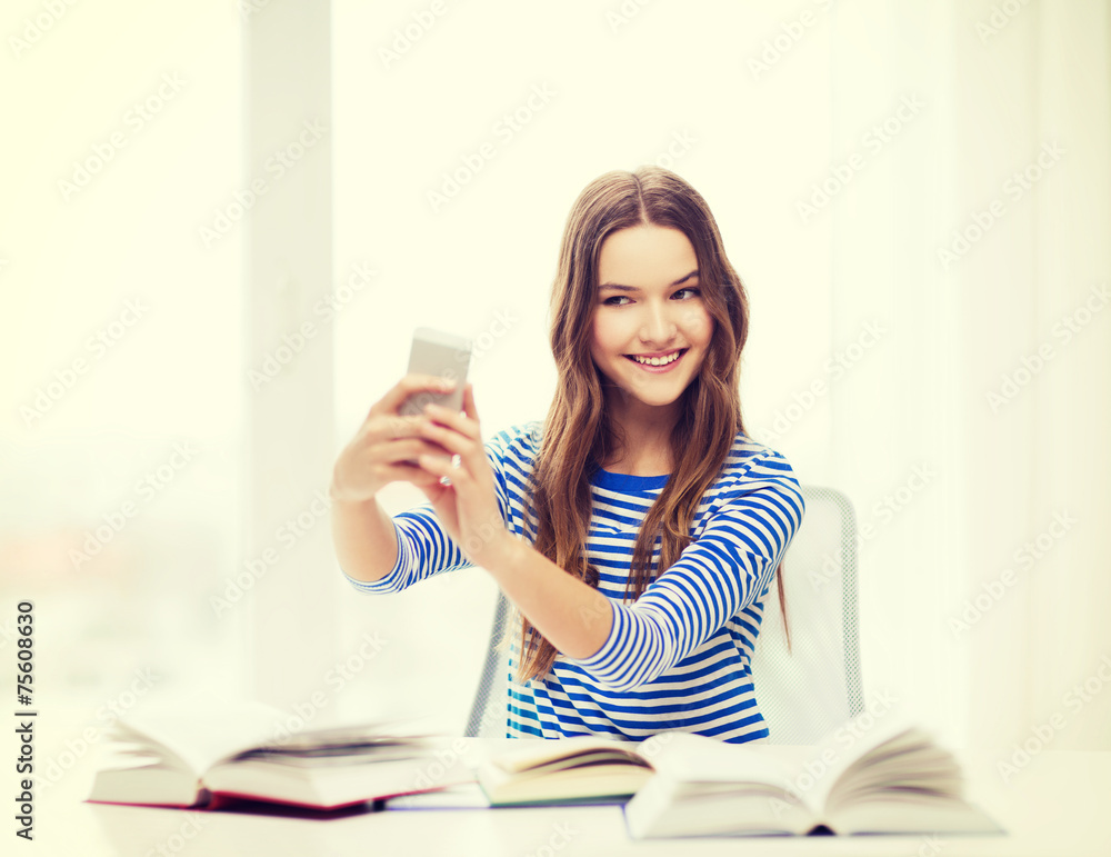 Fototapeta premium smiling student girl with smartphone and books