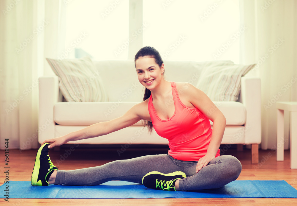 smiling teenage girl streching on floor at home