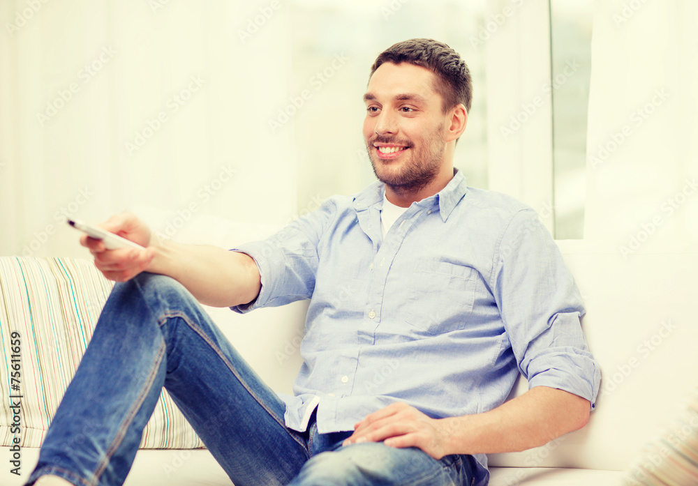 smiling man with tv remote control at home