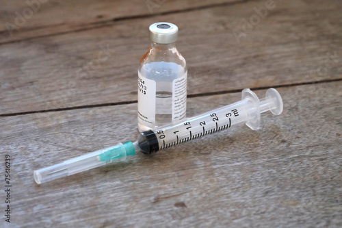 Vaccine in vial with syringe on wooden background