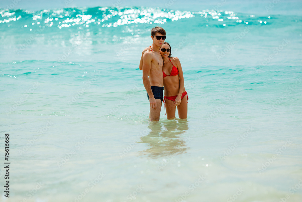 happy couple wearing sunglasses in seawater