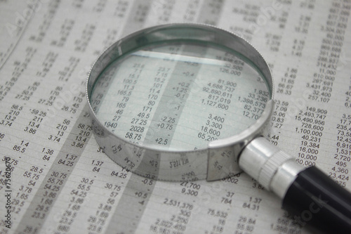Stock price detail financial newspaper with magnifier.