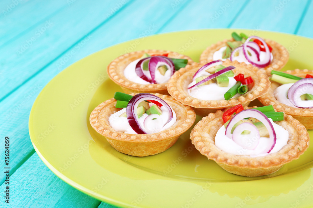 Tartlets with greens and vegetables with sauce on plate on Tartlets with greens and vegetables with sauce on plate on