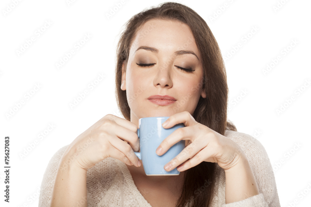 positive young woman enjoying the scent of a cup of tea positive young woman enjoying the scent of a cup of tea