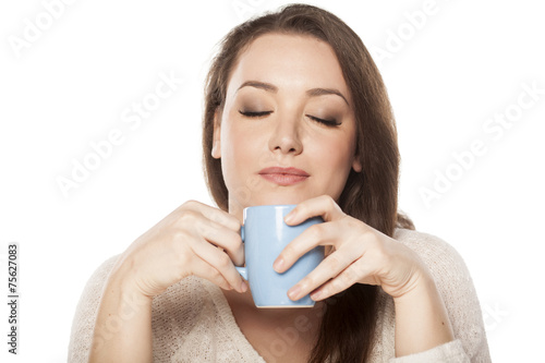 positive young woman enjoying the scent of a cup of tea