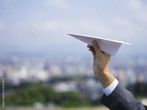 紙飛行機を持つビジネスマンの手