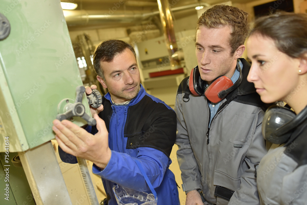 Fototapeta premium Professional teacher showing carpentry machinery to students