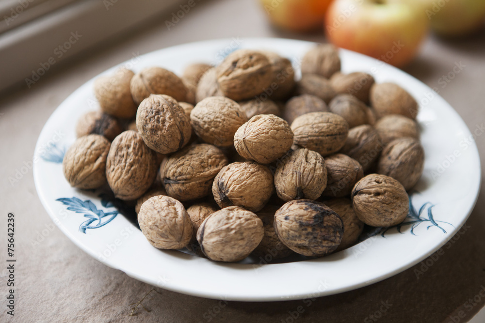A bowl of walnuts on a kitchen table with some apples. Late summer harvest. A bowl of walnuts on a kitchen table with some apples. Late summer harvest.