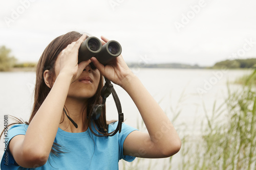 A young girl, a birdwatcher with binoculars. 