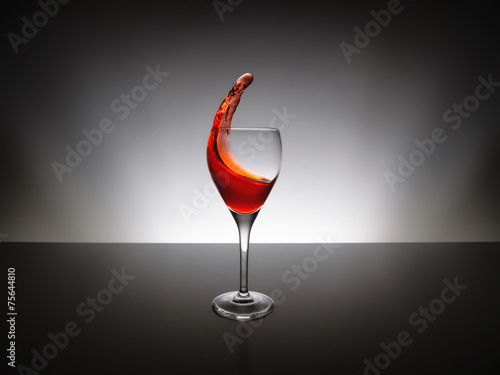 Red wine pour into glass over black background