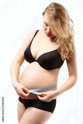 Duży ciążowy brzuch, kobieta mierzy obwód.