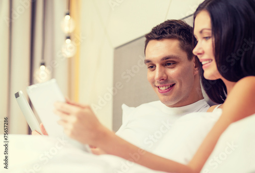 smiling couple in bed with tablet pc computers