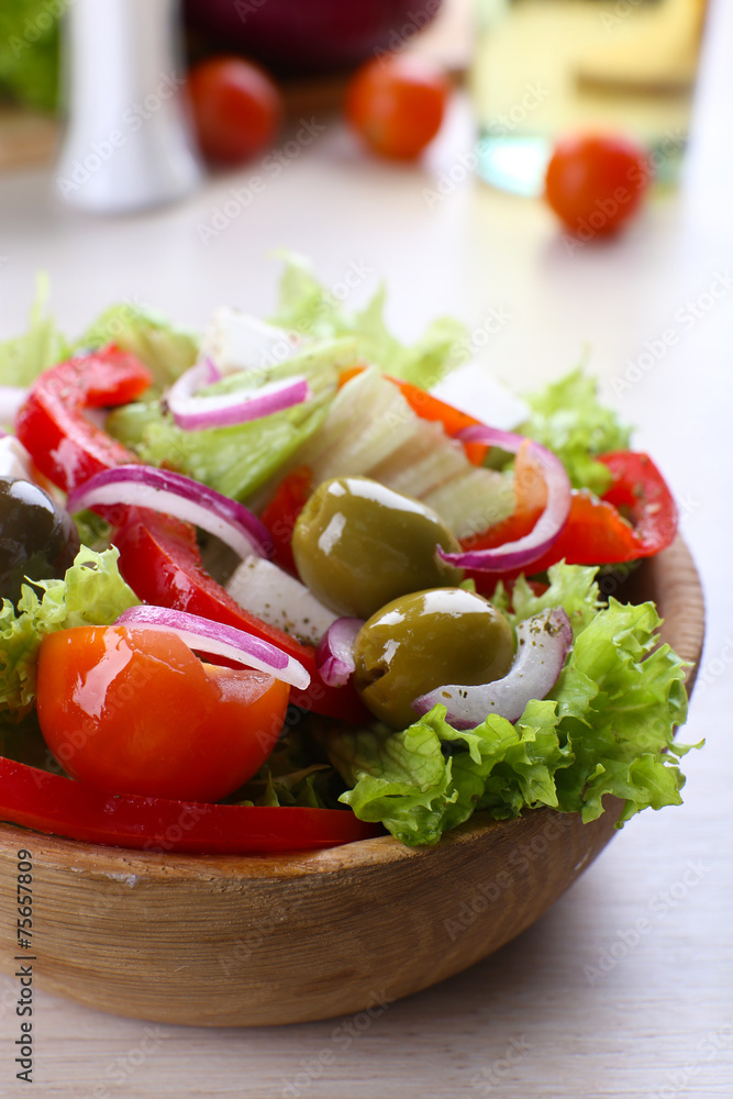 Greek salad in bow on wooden table background