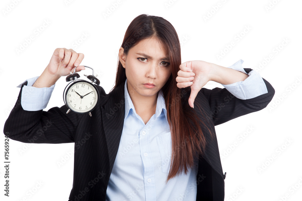 Young Asian businesswoman thumbs down with alarm clock Young Asian businesswoman thumbs down with alarm clock