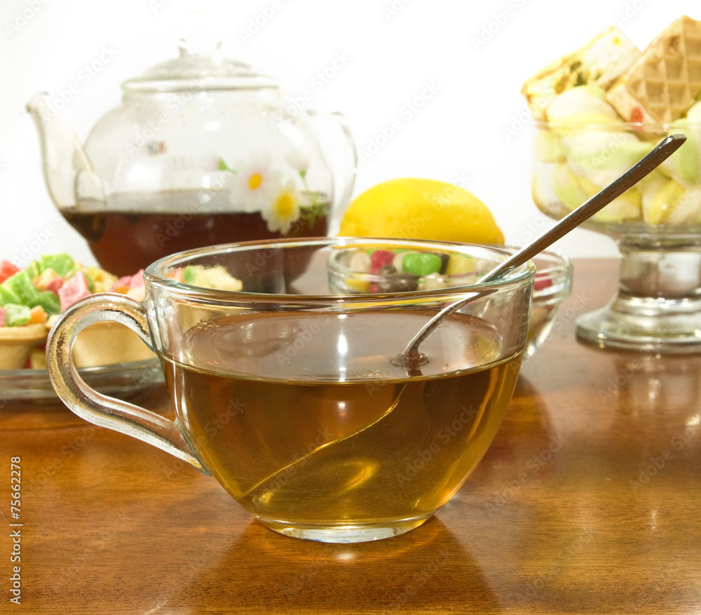 image of a cup of tea, teapot, lemon and cookies closeup image of a cup of tea, teapot, lemon and cookies closeup