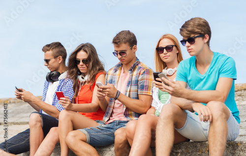 group of friends with smartphones outdoors © Syda Productions
