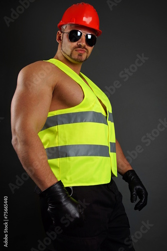 Muscular worker at protective helmet and work vest