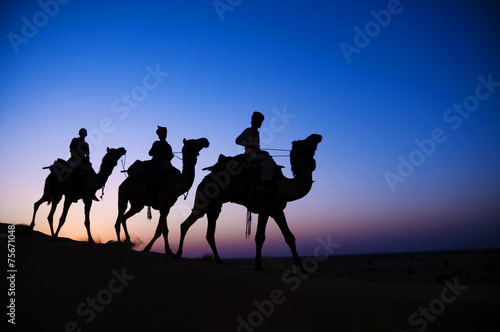Three Inigenous Men Riding Camel Through Desert Concept