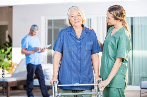 Nurse Assisting Senior Woman To Walk With Zimmer Frame