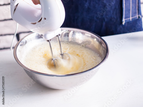Mixing egg cream in bowl with motor mixer, baking cake
