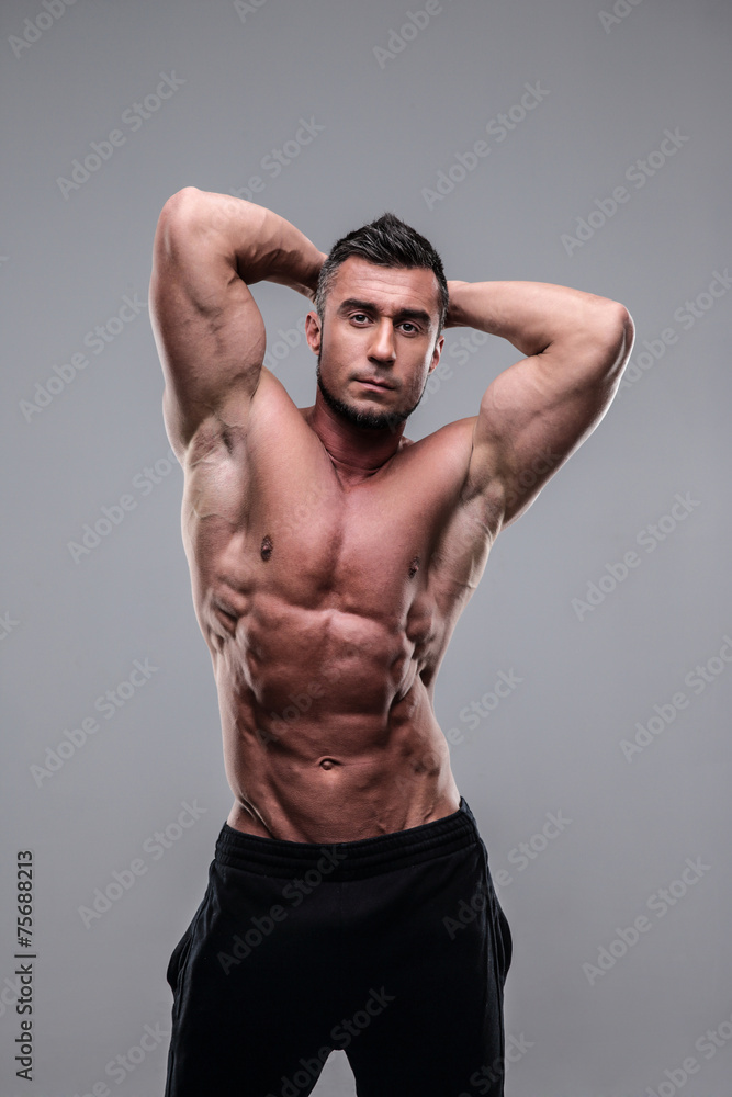 Strong athletic man flexing torso over gray background Strong athletic man flexing torso over gray background