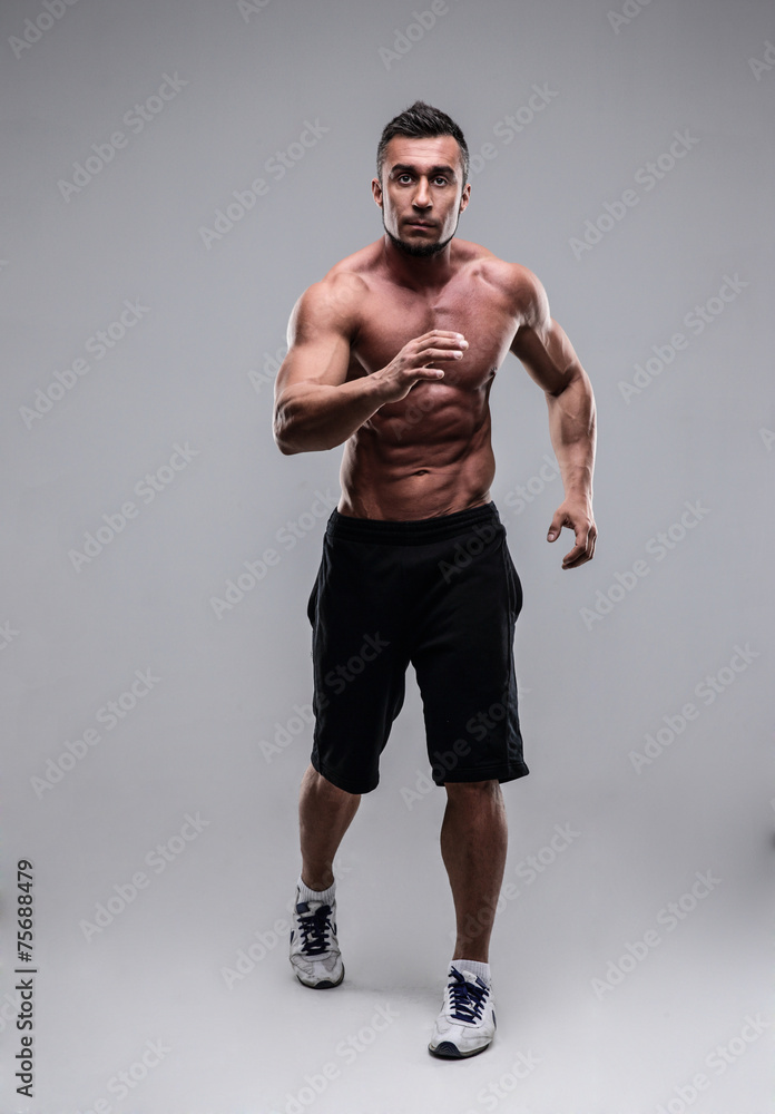 Portrait of a muscular man running over gray background Portrait of a muscular man running over gray background