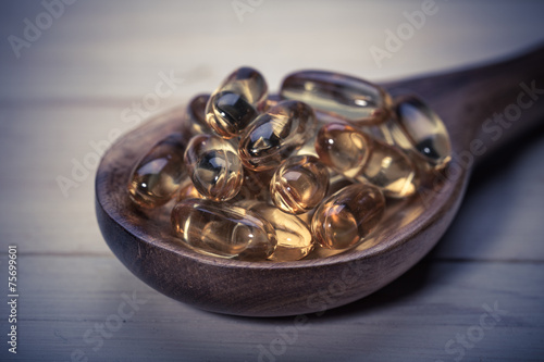 Cod liver oil omega 3 gel capsules isolated on wooden background