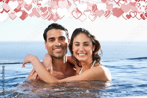 Composite image of smiling couple embracing in the pool
