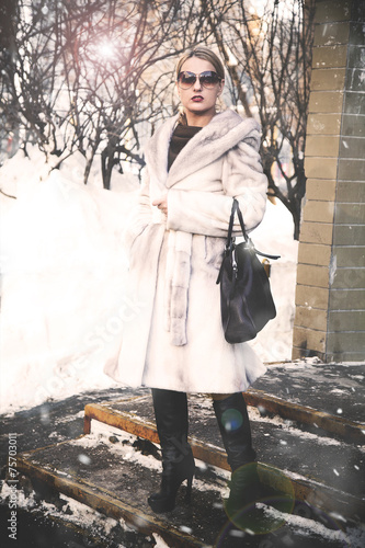 woman standing on the porch in the winter in a white fur coat © Yuli
