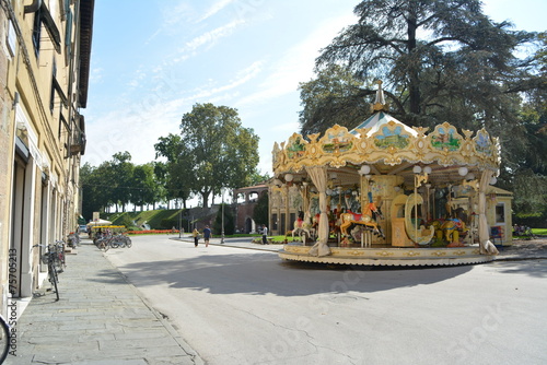 Carousel on its sunny day on an Italian street with bicycles and wooded park