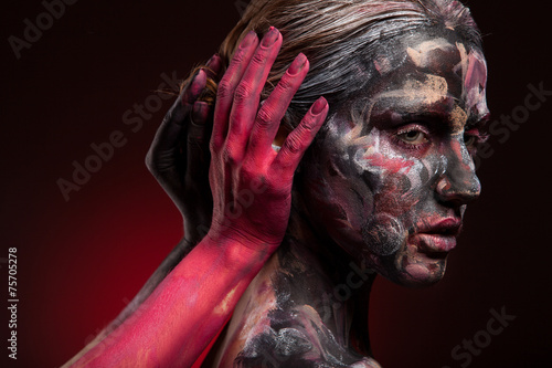 Woman face with colorful bodyart and scarry red hand